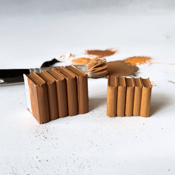 3D-geprinte miniatuurboekenstapels in bruin op een witte ondergrond, van Miniatures Guild