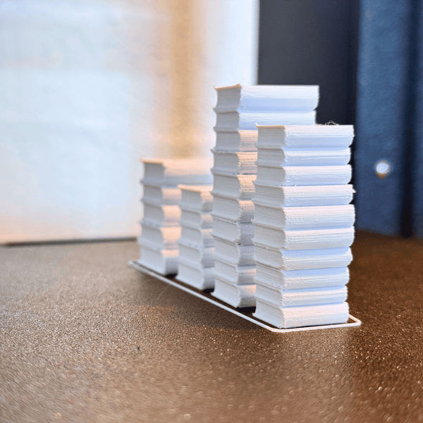 Rijen 3D-geprinte miniatuurboekenstapels in wit, van Miniatures Guild
